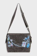 Messenger bag with UV printed charm graphics, adjustable strap, and keychain details