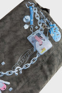 Messenger bag with UV printed charm graphics, adjustable strap, and keychain details