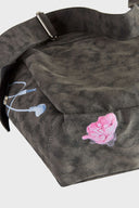 Messenger bag with UV printed charm graphics, adjustable strap, and keychain details
