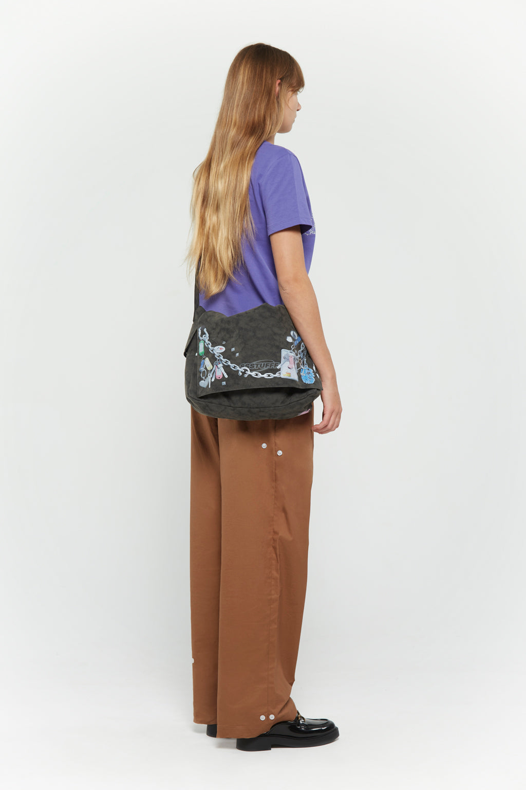 Messenger bag with UV printed charm graphics, adjustable strap, and keychain details