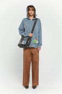 Messenger bag with UV printed charm graphics, adjustable strap, and keychain details