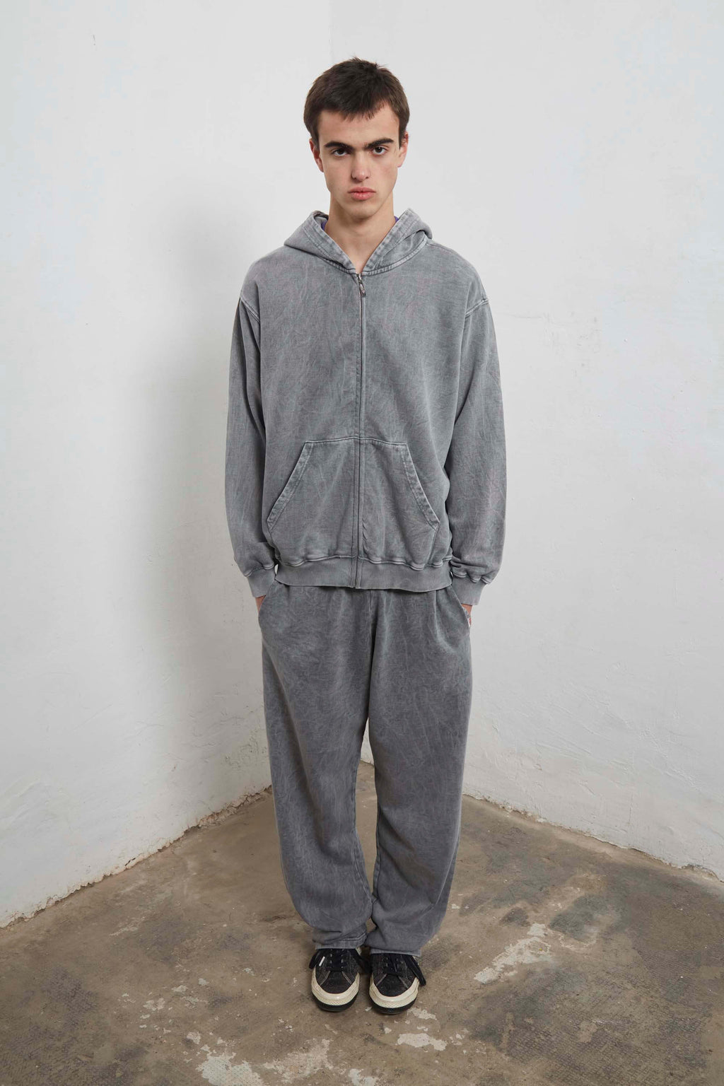 Grey zip-up hoodie with embroidered mini logo on back and black sweatpants with mini logo detail and drawstring waist