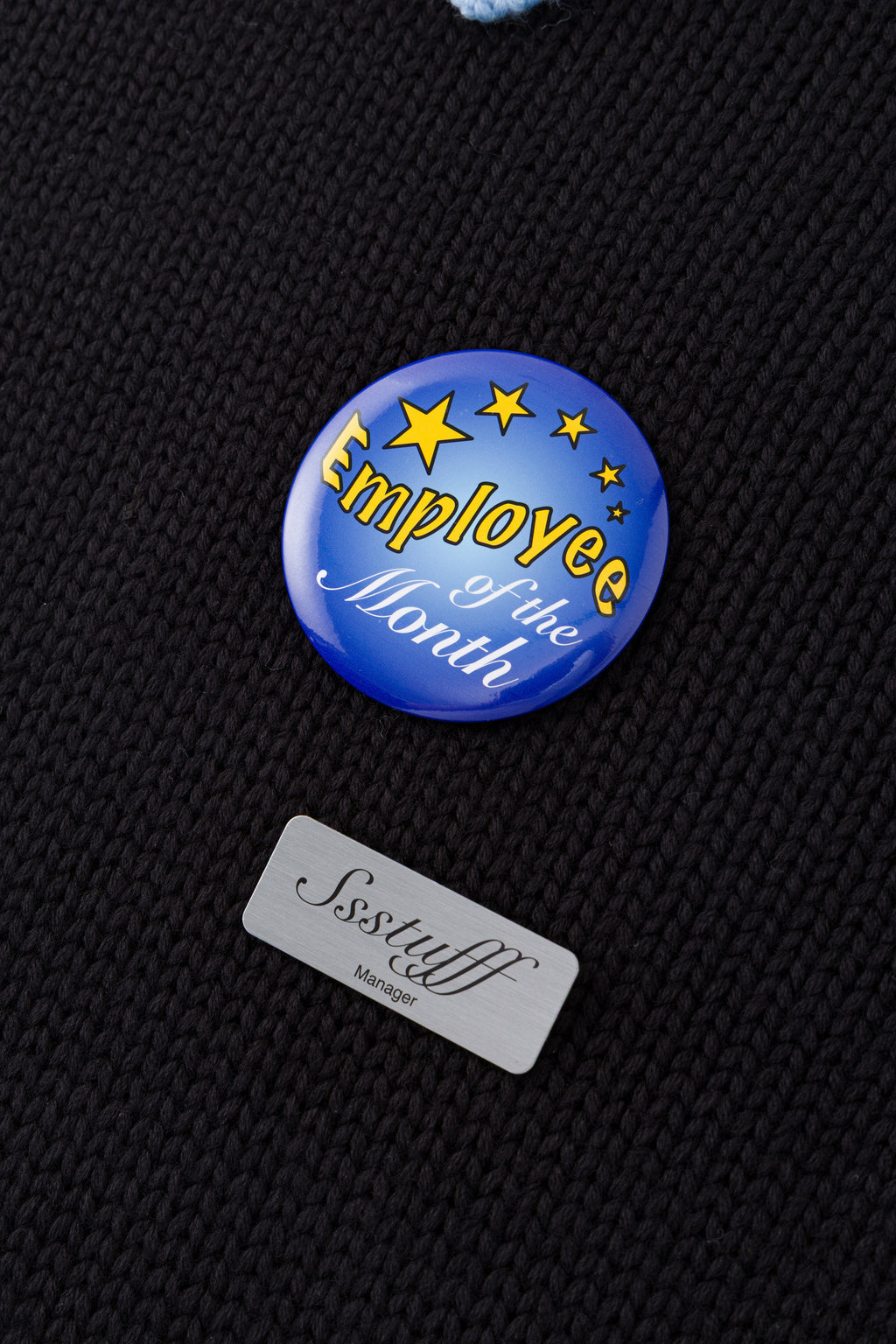 Black knit sweater designed to look like a shirt, with blue collar and attachable name tag and employee of the month pin