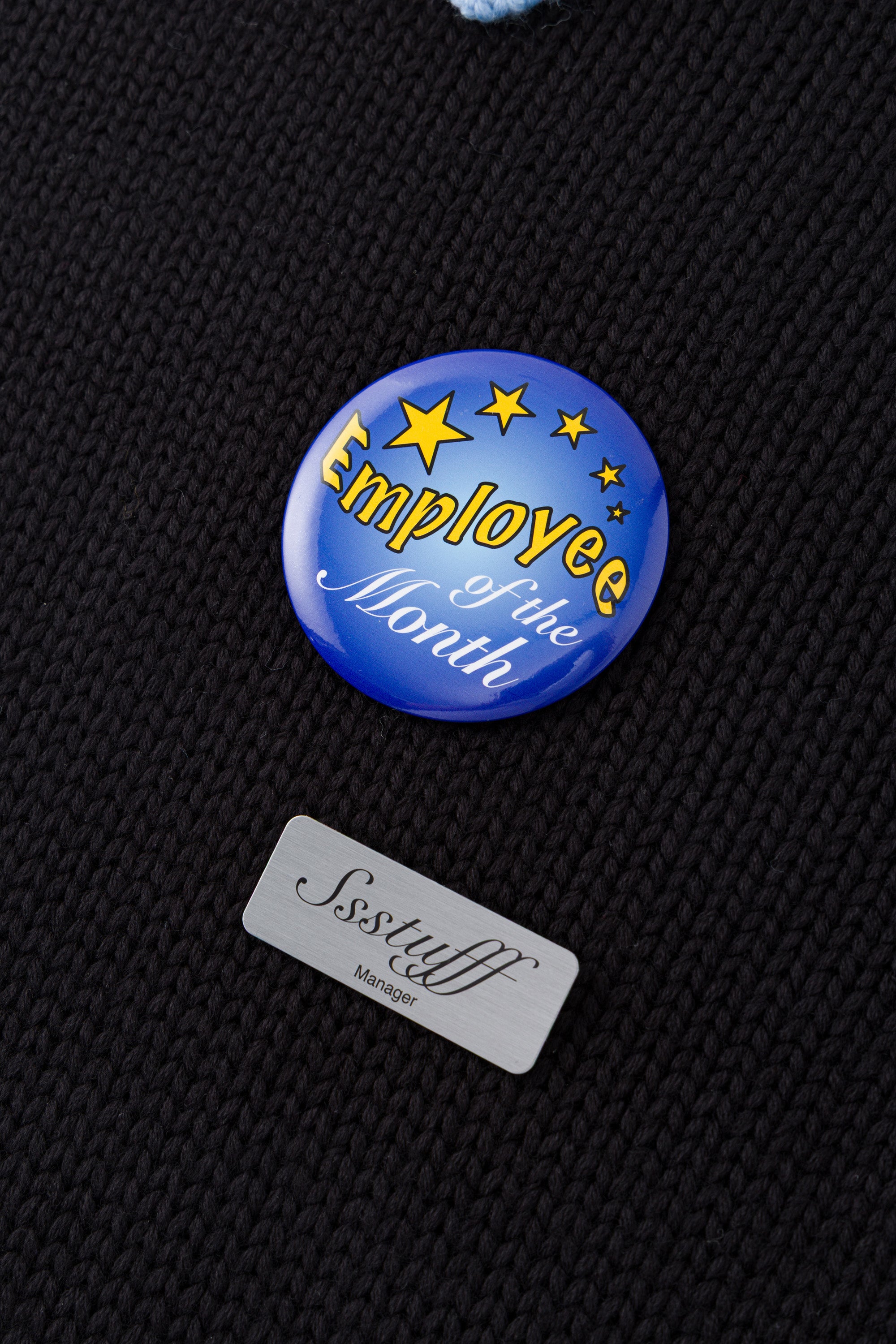 Black knit sweater designed to look like a shirt, with blue collar and attachable name tag and employee of the month pin