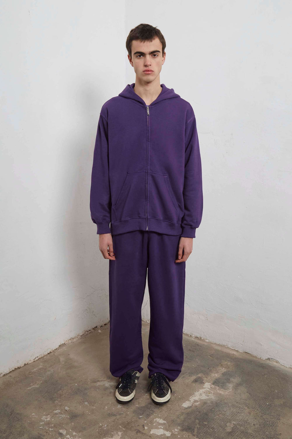 Purple zip-up hoodie with embroidered mini logo on back and black sweatpants with mini logo detail and drawstring waist