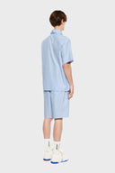 Blue short-sleeved button-up shirt with a pattern of stars and stripes on the chest area.