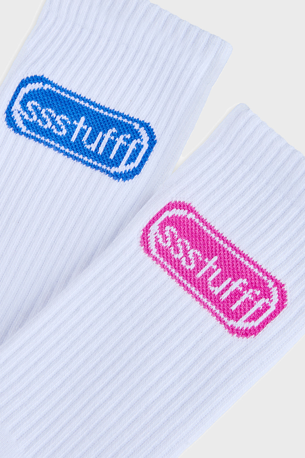 A pair of white ribbed crew socks with knit logos, displayed alongside their packaging 