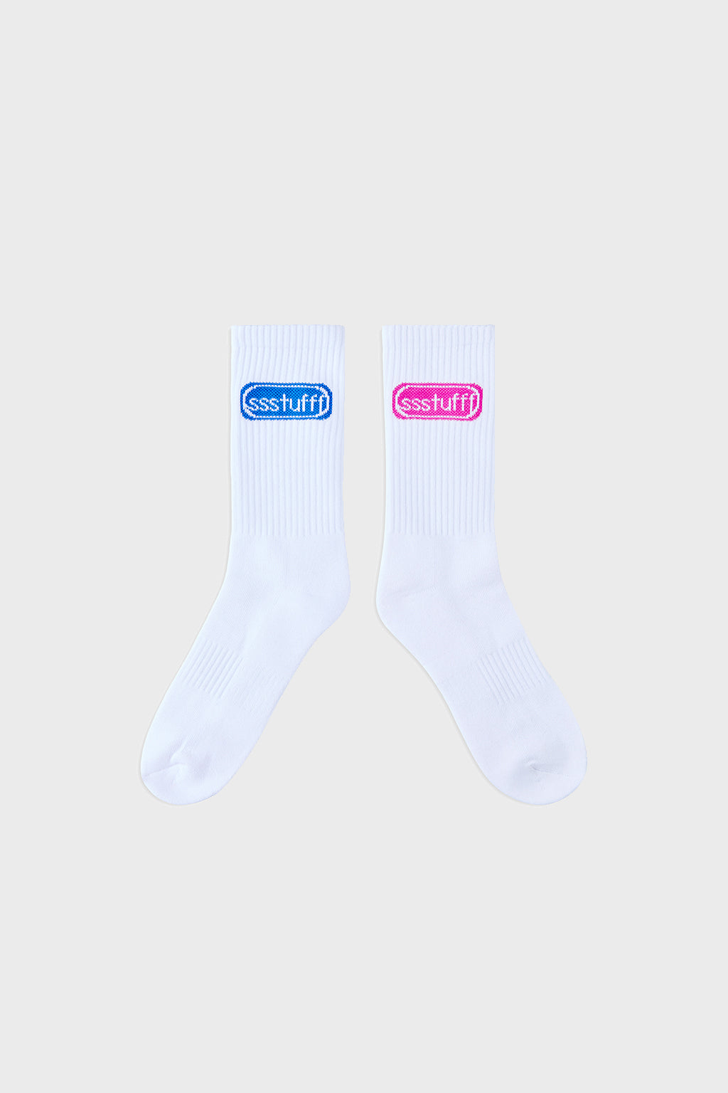 A pair of white ribbed crew socks with knit logos, displayed alongside their packaging 