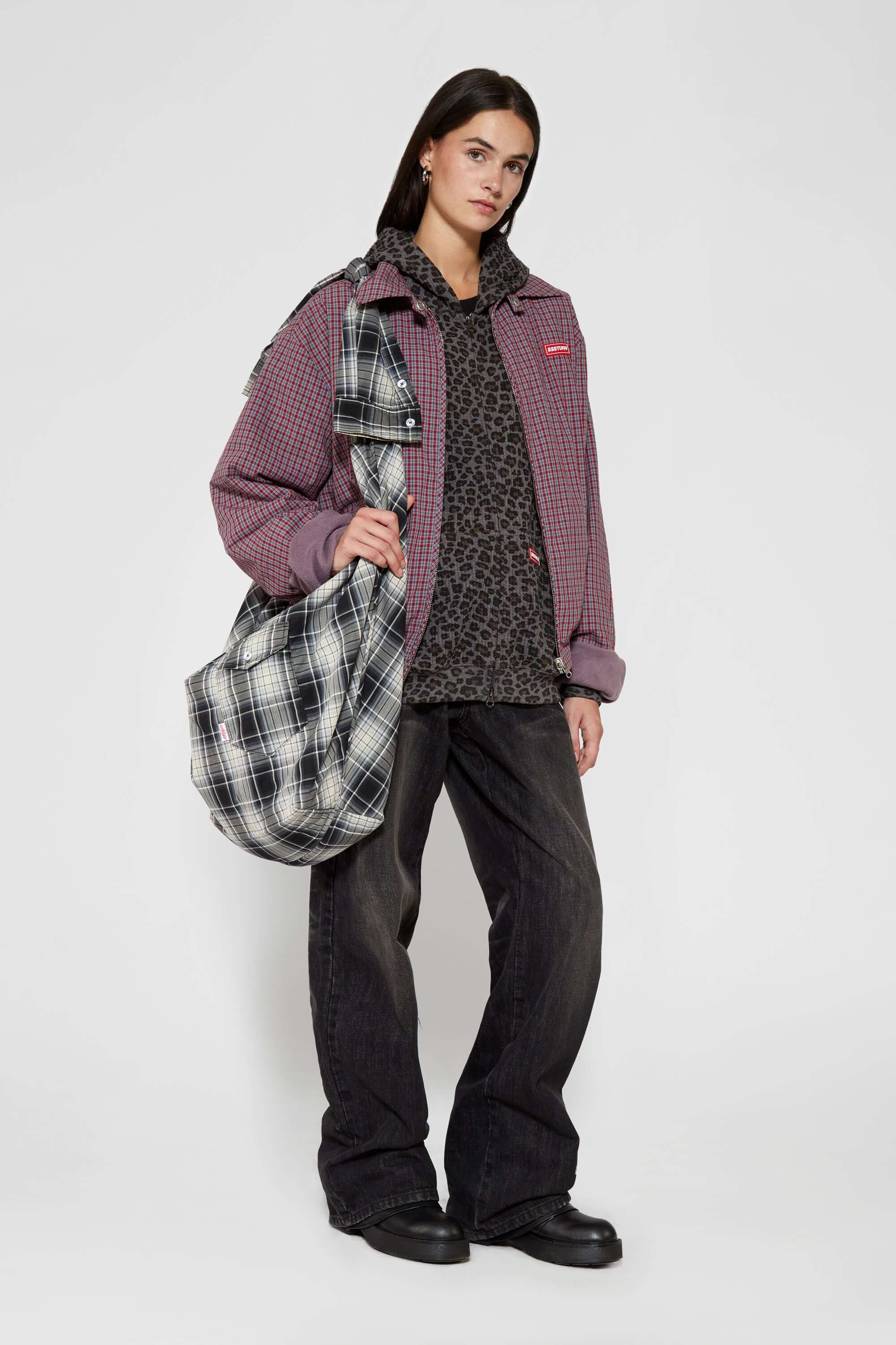 Black and white checked croissant-shaped bag with shirt texture and adjustable sleeve handles for shoulder or crossbody wear