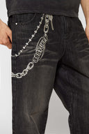 Black wash denim jeans with embroidered keychain, carabiner, and earphone charm details, and pin embroidery on ankle