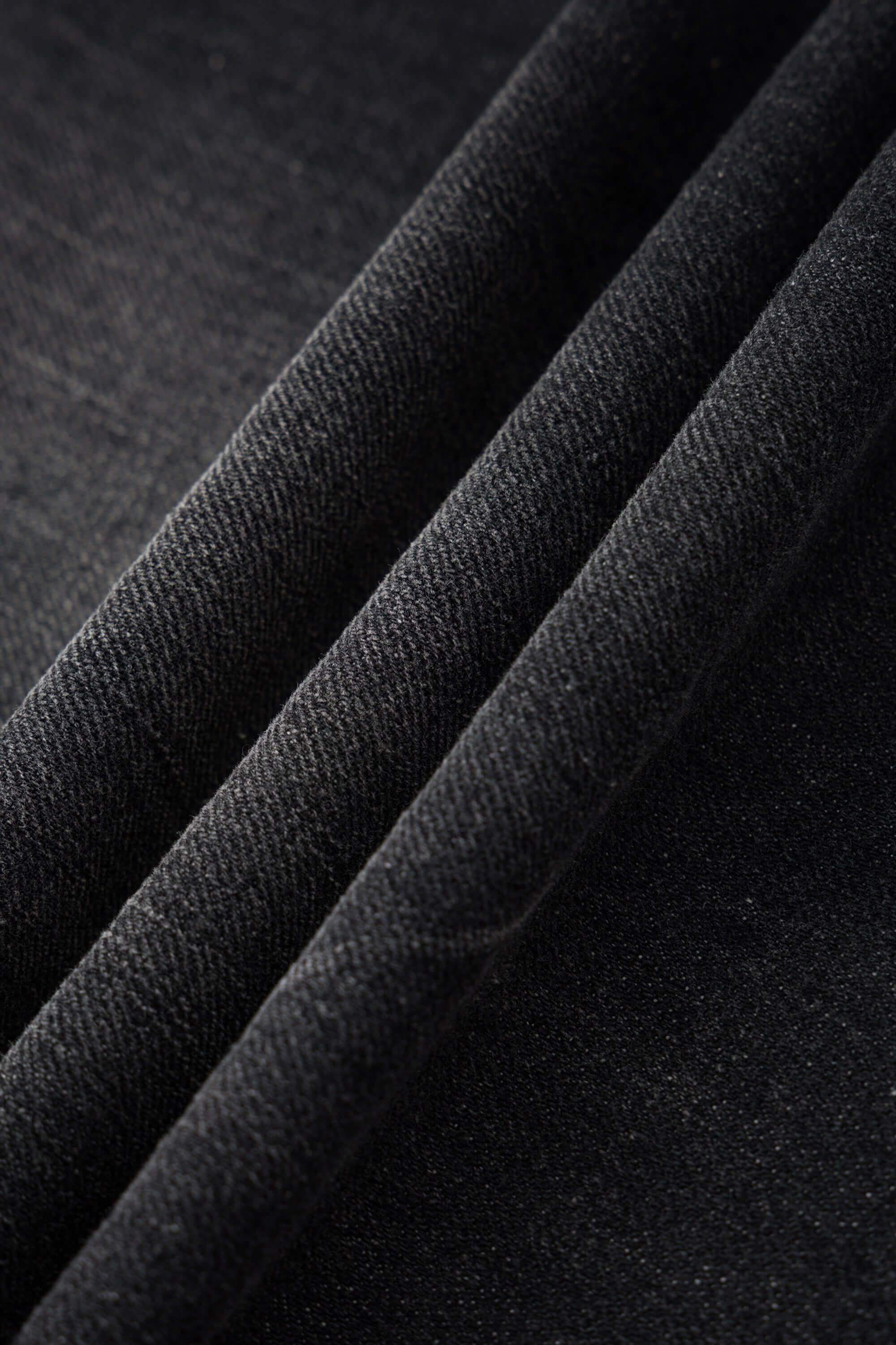 Black wash denim jeans with embroidered keychain, carabiner, and earphone charm details, and pin embroidery on ankle
