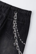 Black wash denim jeans with embroidered keychain, carabiner, and earphone charm details, and pin embroidery on ankle