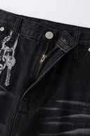 Black wash denim jeans with embroidered keychain, carabiner, and earphone charm details, and pin embroidery on ankle