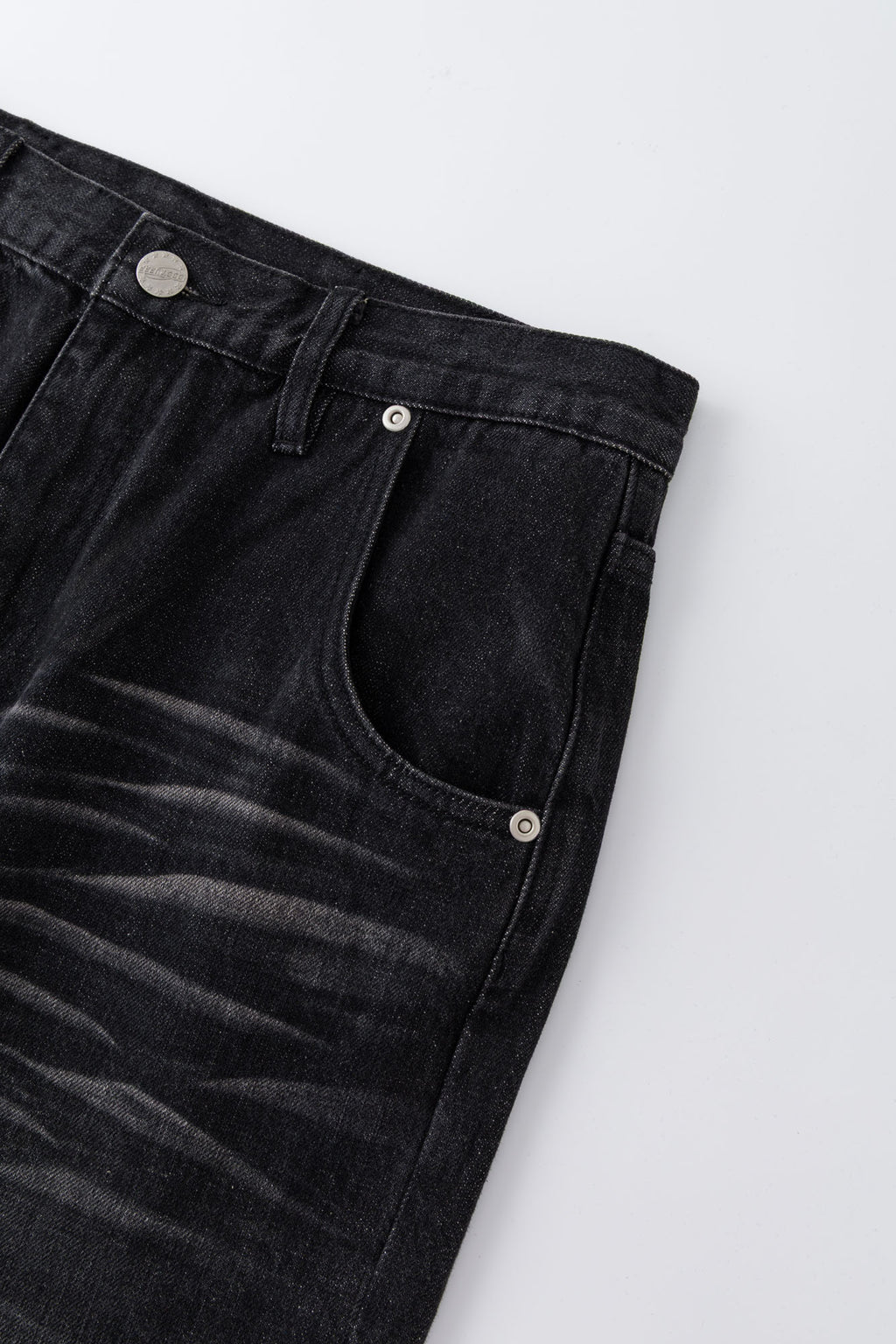 Black wash denim jeans with embroidered keychain, carabiner, and earphone charm details, and pin embroidery on ankle