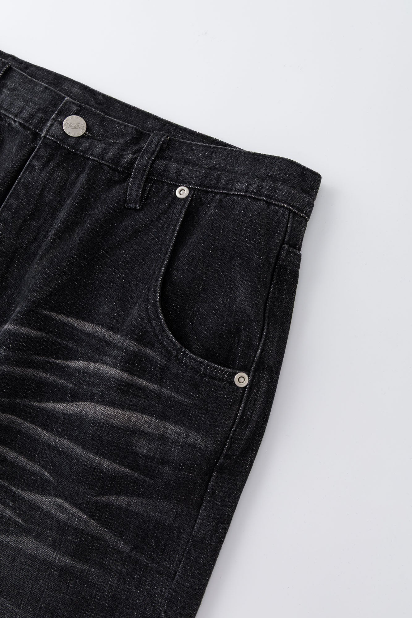 Black wash denim jeans with embroidered keychain, carabiner, and earphone charm details, and pin embroidery on ankle