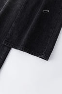 Black wash denim jeans with embroidered keychain, carabiner, and earphone charm details, and pin embroidery on ankle