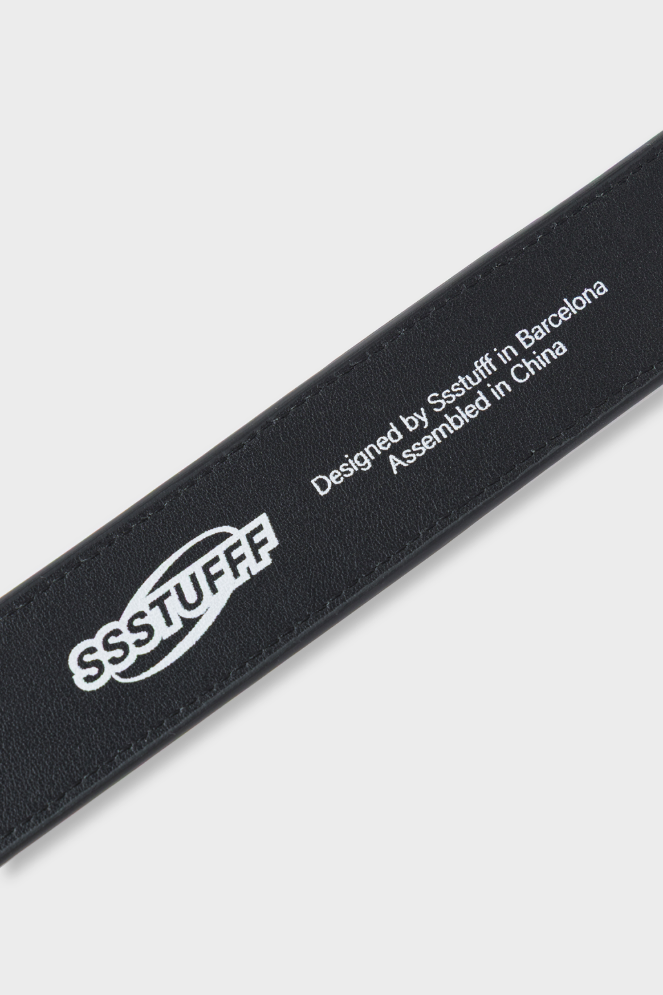 Black leather belt featuring a red and white square buckle designed to resemble a classic iPod Shuffle music player.