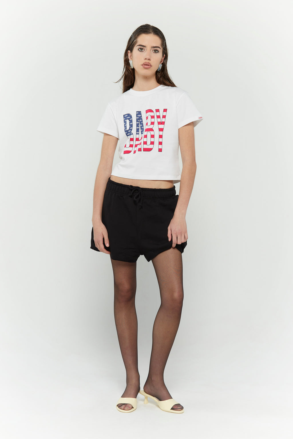 White crew neck t-shirt with the text 'BABY' digitally printed in bold letters with the American flag 
