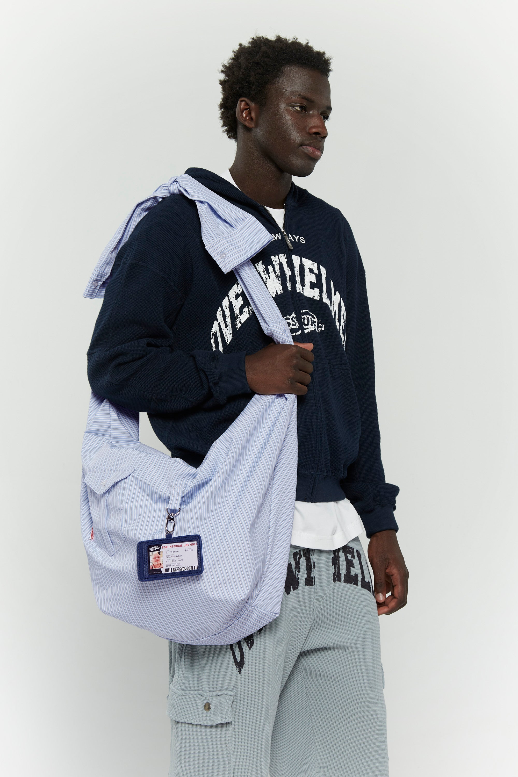Blue striped croissant-shaped bag with shirt texture and adjustable sleeve handles for shoulder or crossbody wear, includes leather cardholder