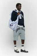 Blue striped croissant-shaped bag with shirt texture and adjustable sleeve handles for shoulder or crossbody wear, includes leather cardholder