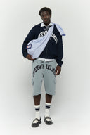 Blue striped croissant-shaped bag with shirt texture and adjustable sleeve handles for shoulder or crossbody wear, includes leather cardholder