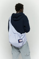 Blue striped croissant-shaped bag with shirt texture and adjustable sleeve handles for shoulder or crossbody wear, includes leather cardholder