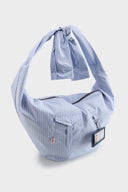 Blue striped croissant-shaped bag with shirt texture and adjustable sleeve handles for shoulder or crossbody wear, includes leather cardholder