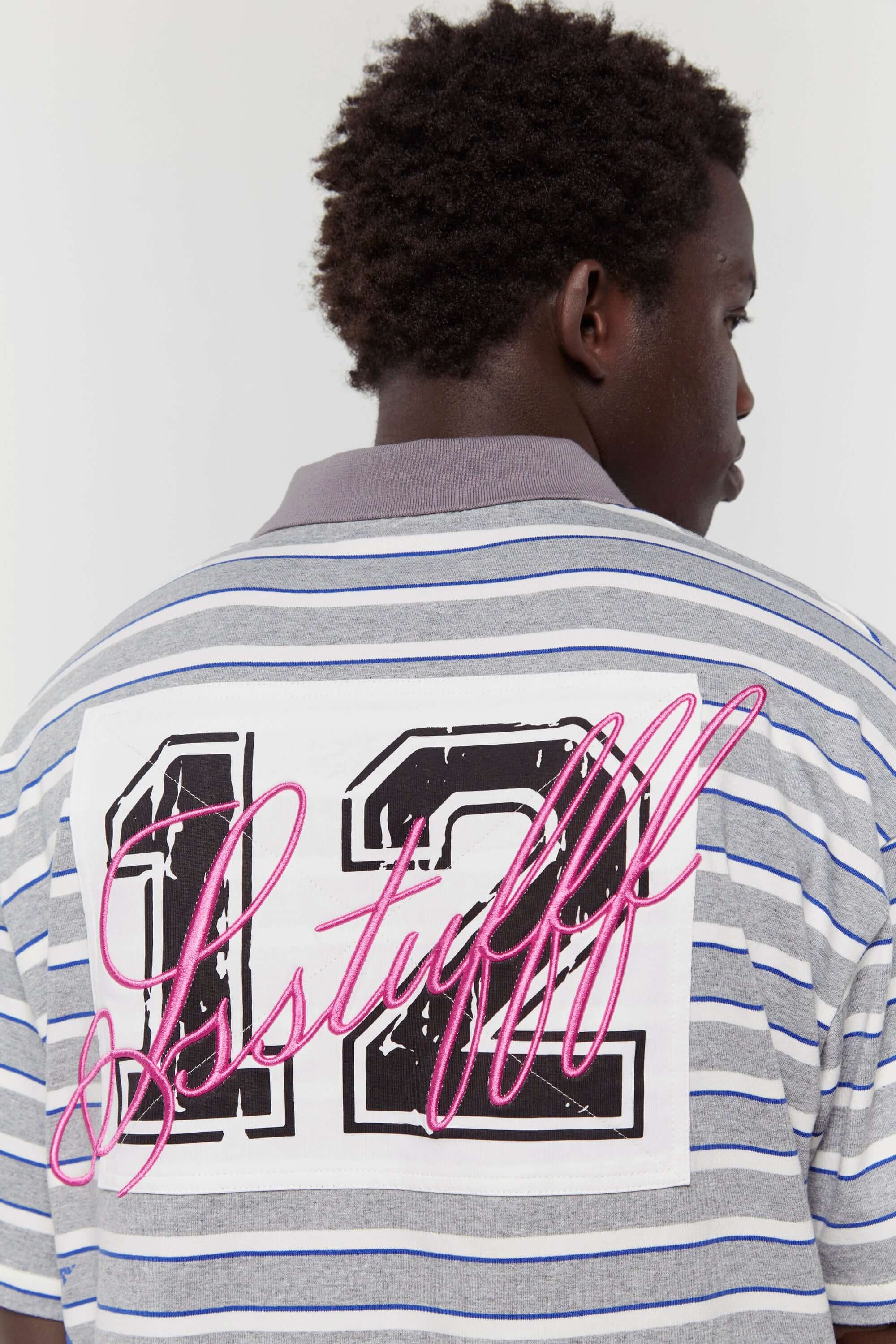 Grey striped polo shirt with embroidery, PVC, and screenprint graphics inspired by retro birthday party style