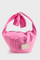 Pink croissant-shaped bag with shirt texture and adjustable sleeve handles for shoulder or crossbody wear, includes leather cardholder