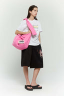 Pink croissant-shaped bag with shirt texture and adjustable sleeve handles for shoulder or crossbody wear, includes leather cardholder