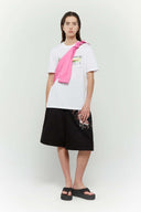 Pink croissant-shaped bag with shirt texture and adjustable sleeve handles for shoulder or crossbody wear, includes leather cardholder