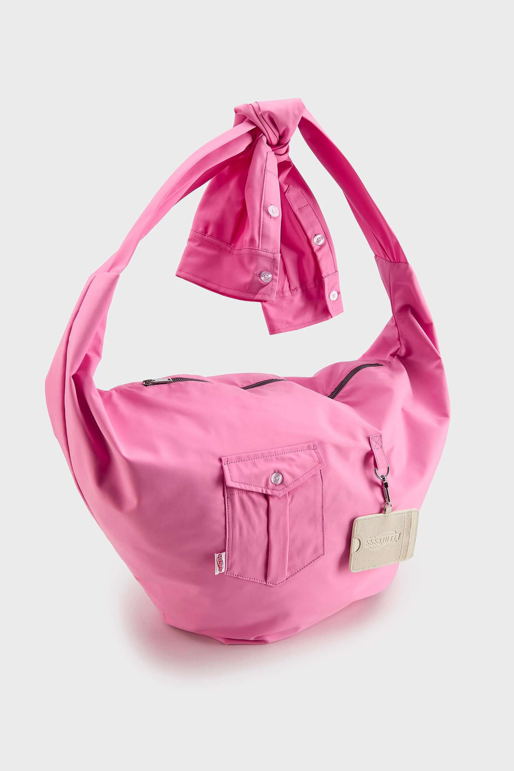 Pink croissant-shaped bag with shirt texture and adjustable sleeve handles for shoulder or crossbody wear, includes leather cardholder