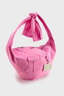 Pink croissant-shaped bag with shirt texture and adjustable sleeve handles for shoulder or crossbody wear, includes leather cardholder