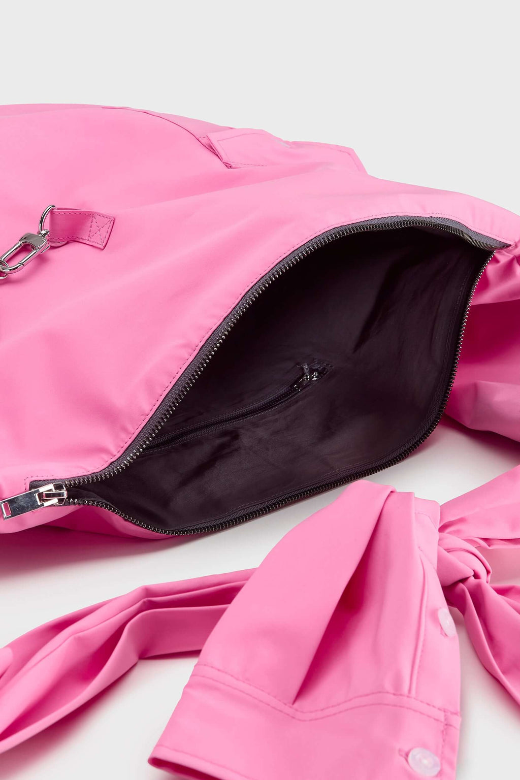 Pink croissant-shaped bag with shirt texture and adjustable sleeve handles for shoulder or crossbody wear, includes leather cardholder