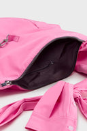 Pink croissant-shaped bag with shirt texture and adjustable sleeve handles for shoulder or crossbody wear, includes leather cardholder