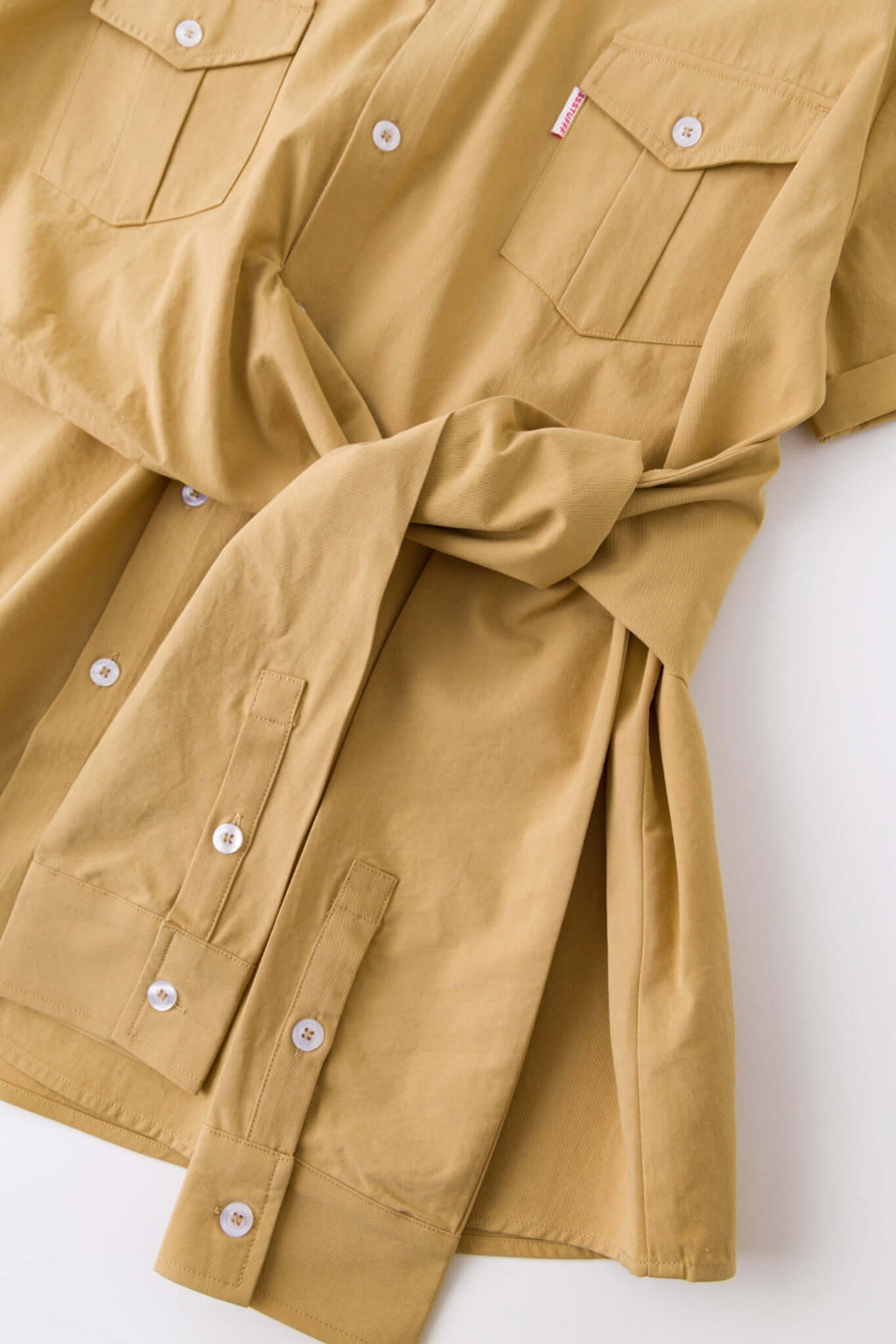 Beige shirt with 4 sleeves making a tie waist 

