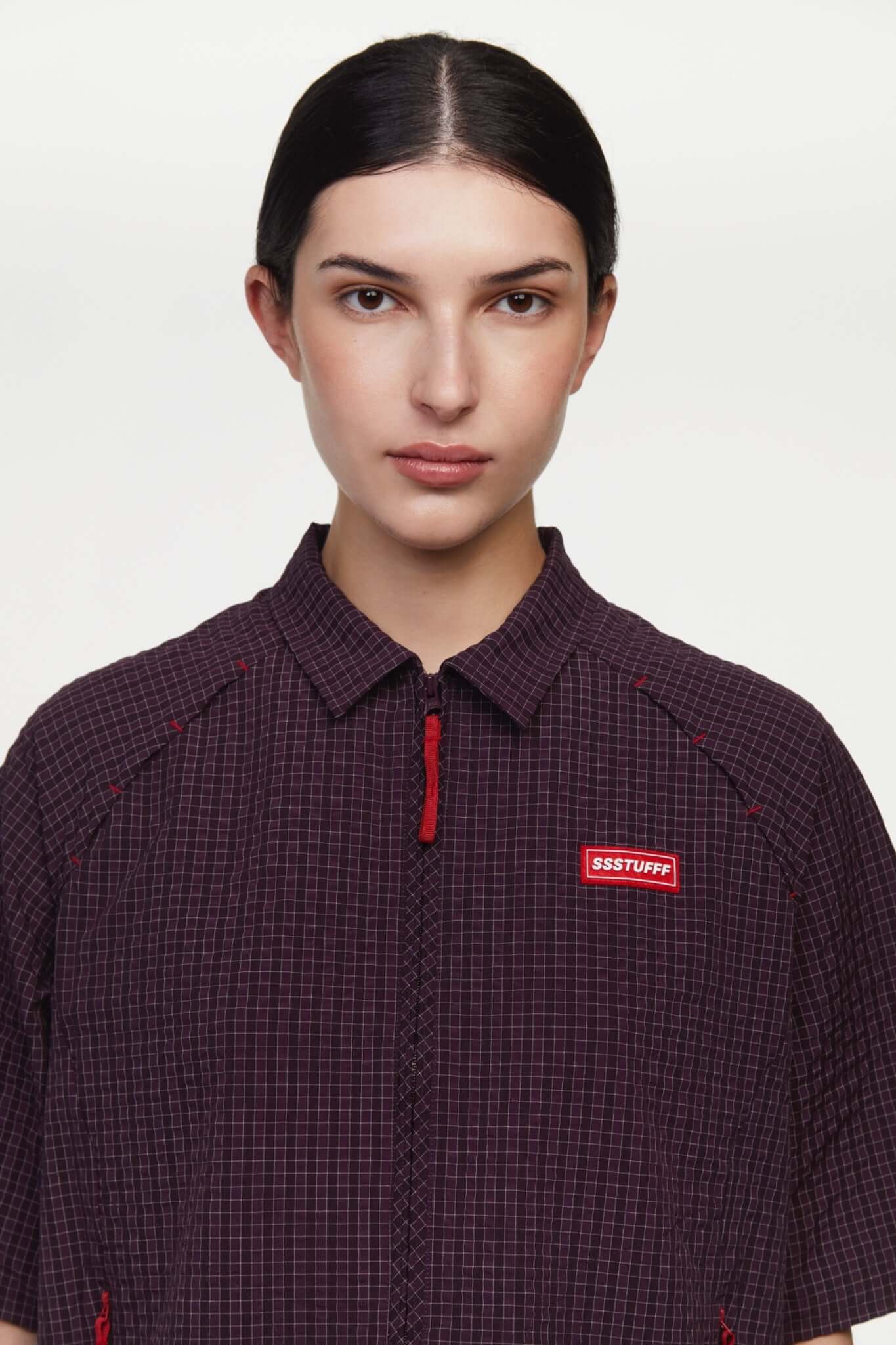 Burgundy checkered shirt with a red logo and red details in the zipper
