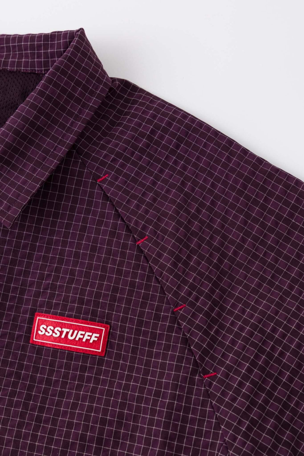 Burgundy checkered shirt with a red logo and red details in the zipper
