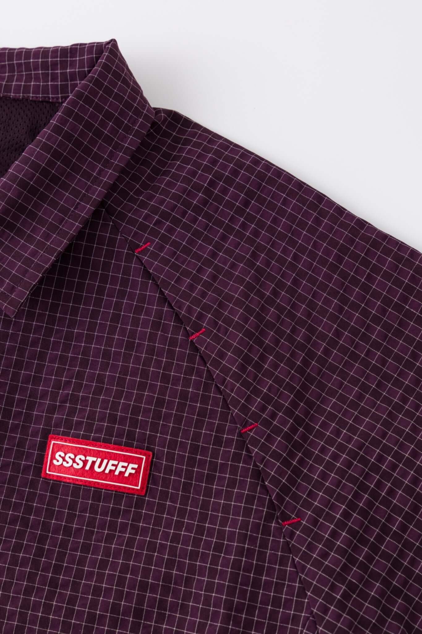 Burgundy checkered shirt with a red logo and red details in the zipper
