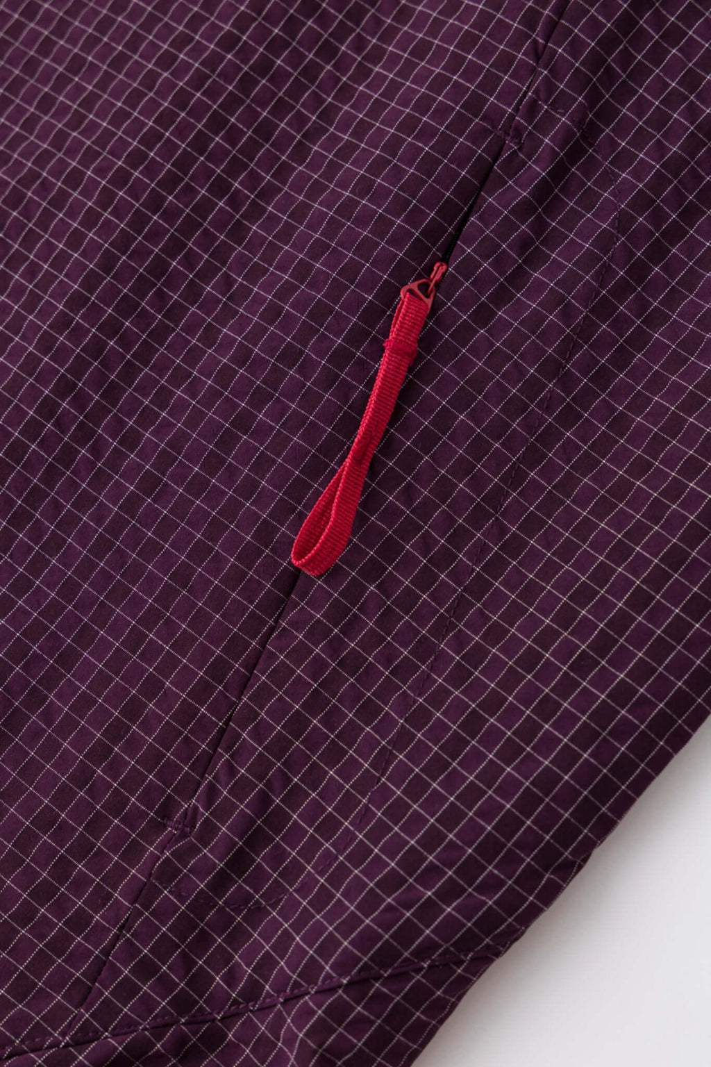 Burgundy checkered shirt with a red logo and red details in the zipper
