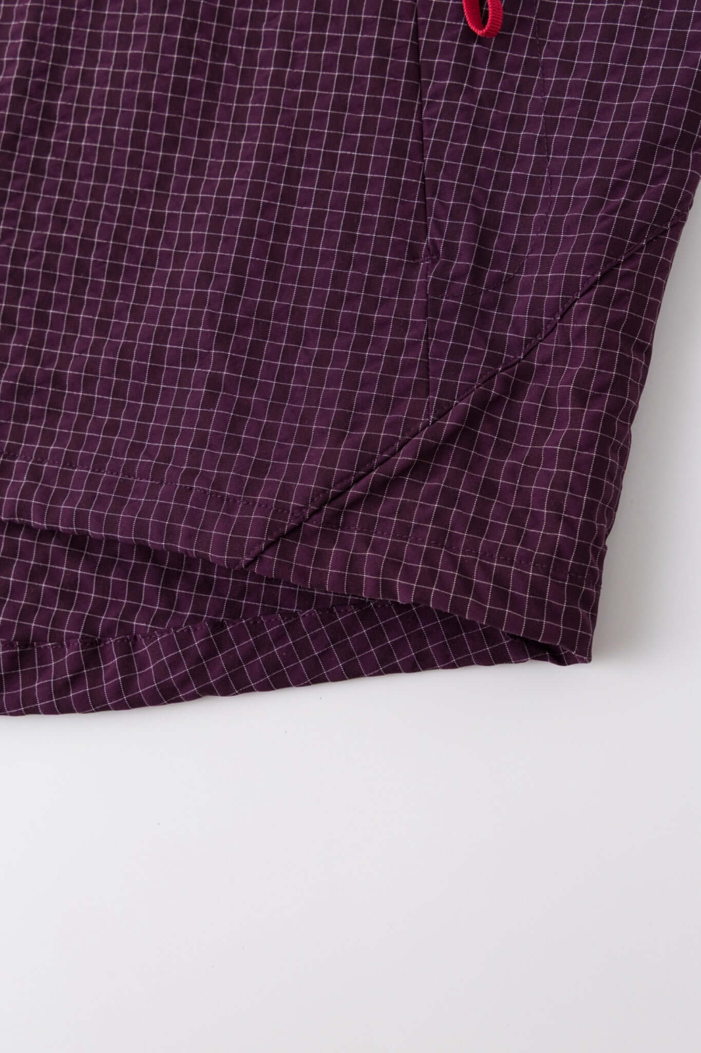 Burgundy checkered shirt with a red logo and red details in the zipper

