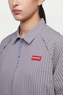 Grey checkered shirt with a red logo and red details in the zipper
