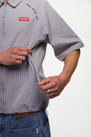 Grey checkered shirt with a red logo and red details in the zipper
