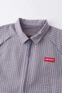 Grey checkered shirt with a red logo and red details in the zipper
