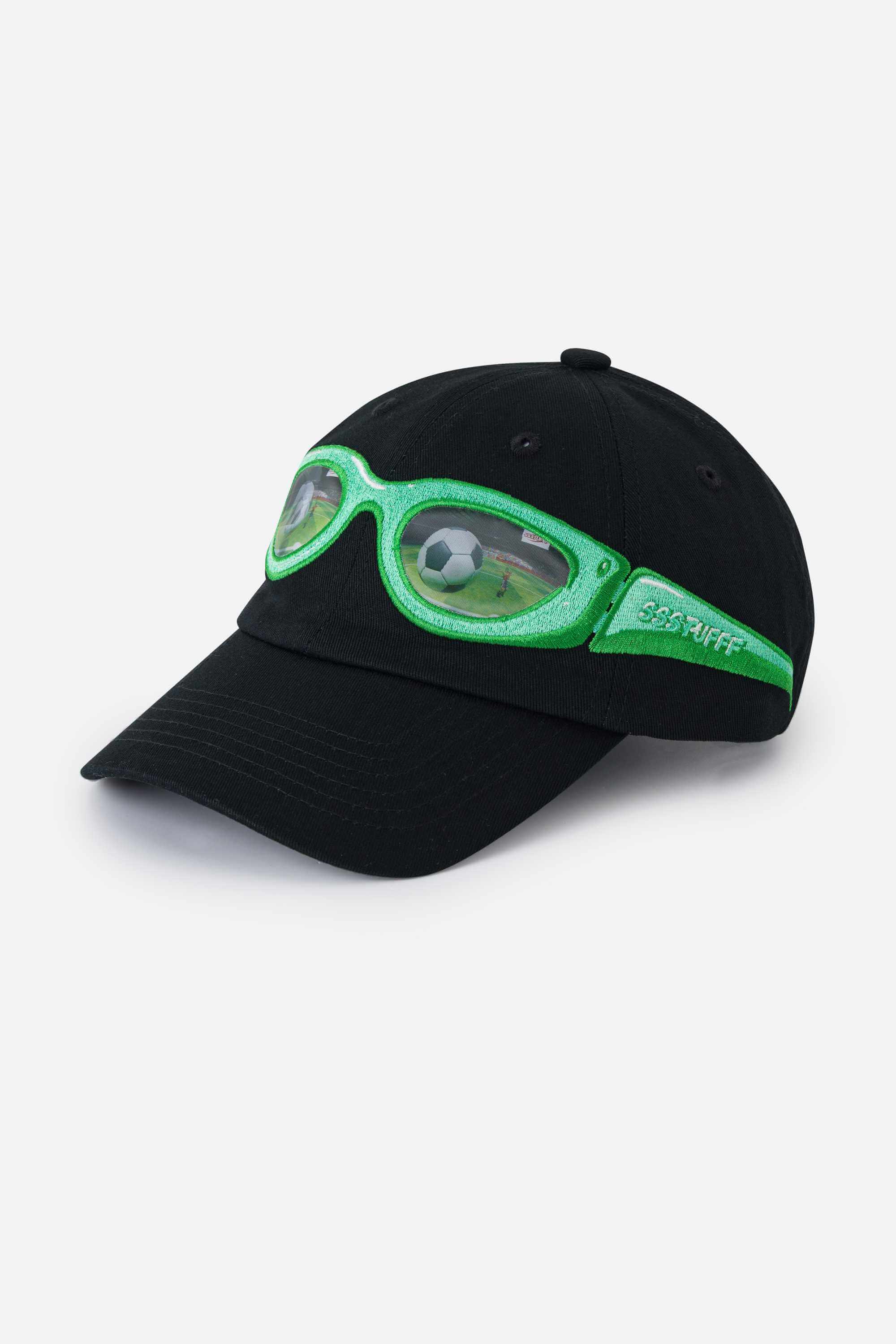 Black cap with green sunglasses design on a white background. The lens of the glasses has a lenticular effect with a football ball inside a goal