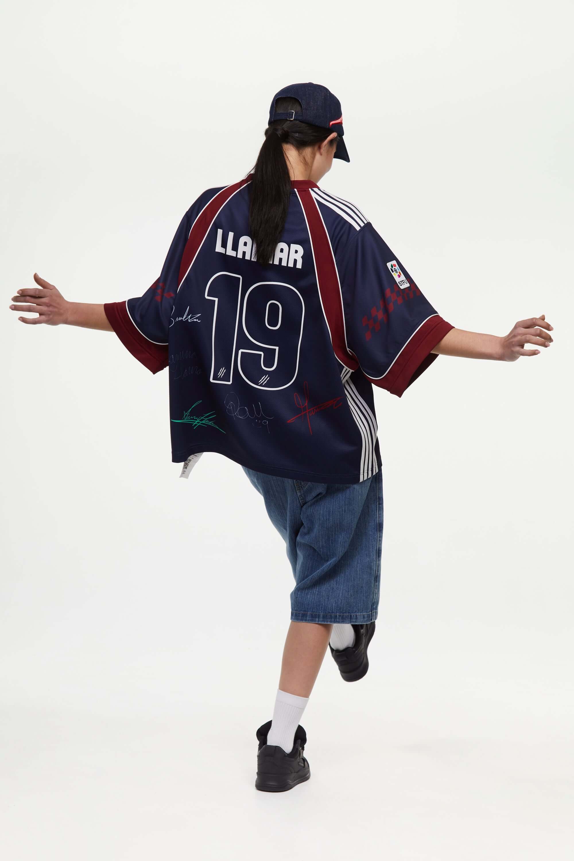 Person wearing a navy sports jersey signed, with red accents,  with 'LLAMAR' and number '19' in white, on a white background
