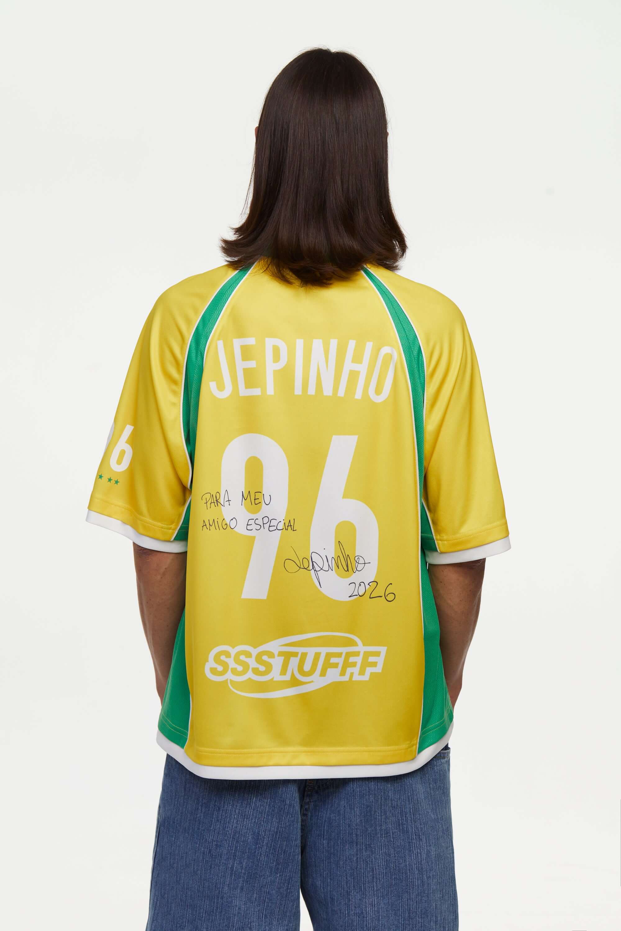 Person wearing a yellow and green sports jersey with 'Jepinho' and '96' signed on a white background