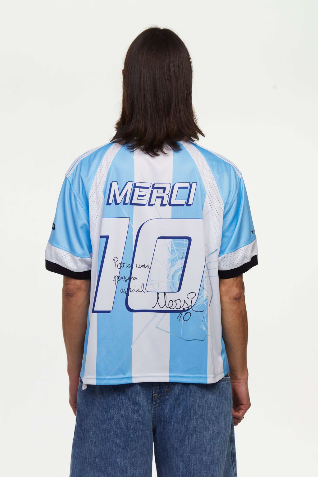 Person wearing a light blue and white striped jersey signed with 'MERCI' and number '10' on the back, standing against a white background.