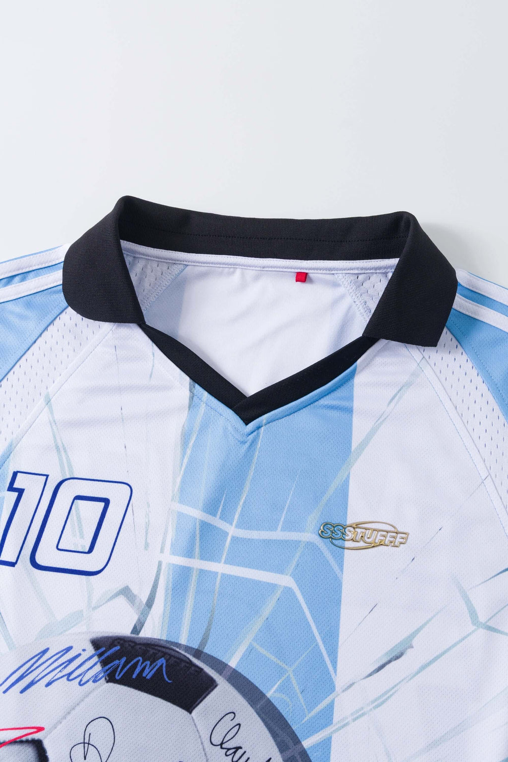 Close-up of a light blue and white sports jersey signed with a number '10' and brand logo on a white background