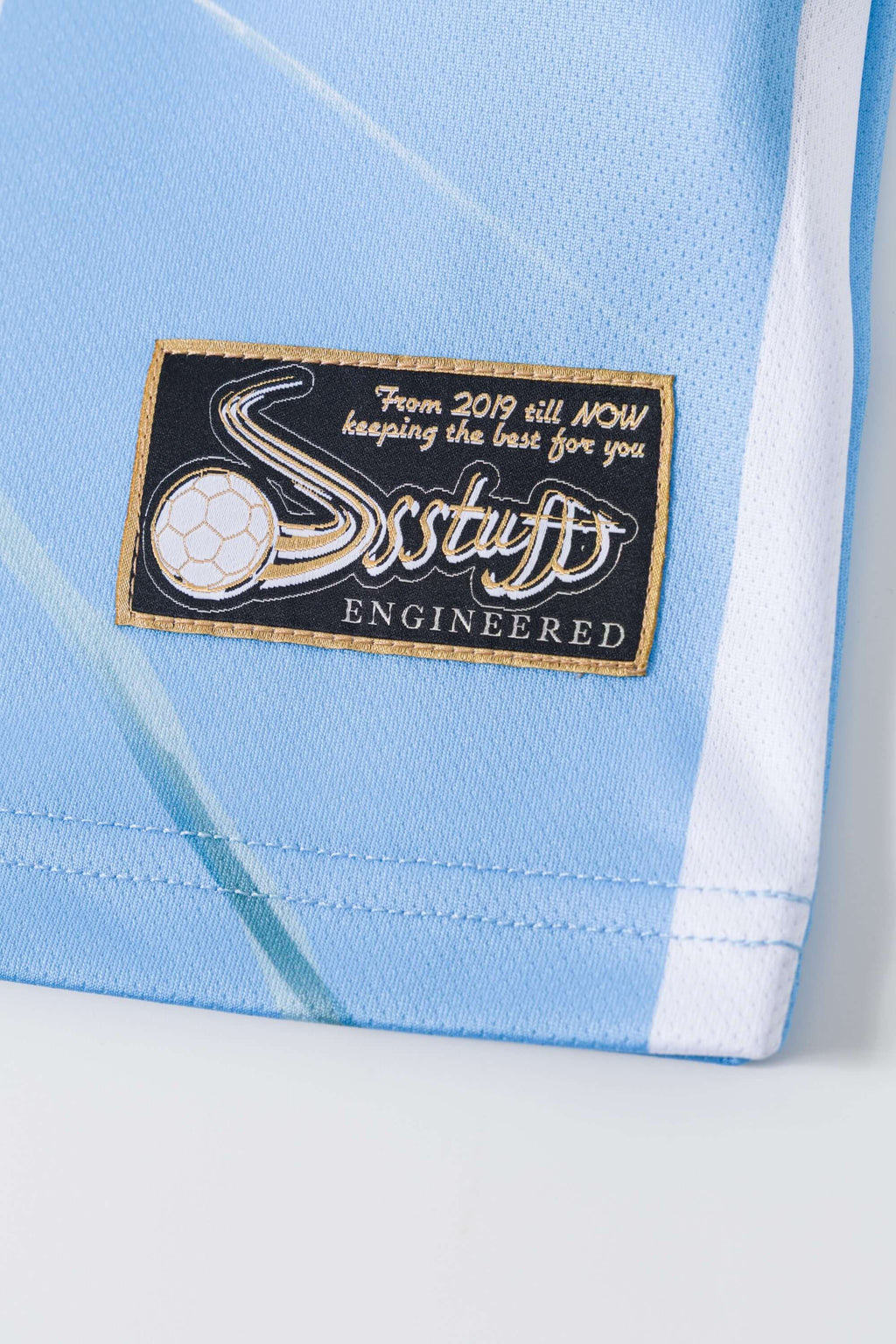 Close-up of a light blue and white sports jersey with a brand label on a white background